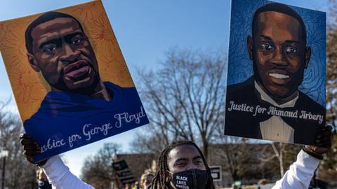 A protester holds placards with the pictures of George Floyd and Ahmaud Arbery on them