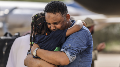 Violinist Othmano, hugging his daughter at Wadi Seidna airport in Khartoum, Sudan, before boarding an RAF C-130 that will take them to Cyprus