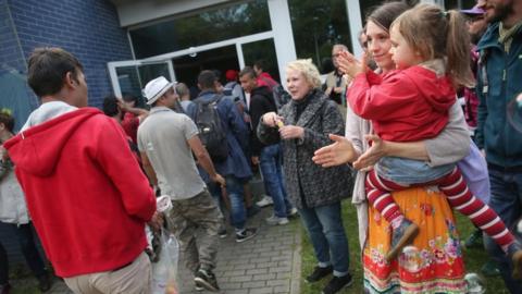 Migrants who had arrived on a train hours earlier arrive to locals welcoming them with soap bubbles and balloons at the Jahn-Sporthalle gymnasium in Neukoelln district on 8 September 8 2015 in Berlin