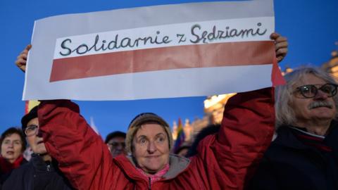 A protester holds a sign reading solidarity with judges