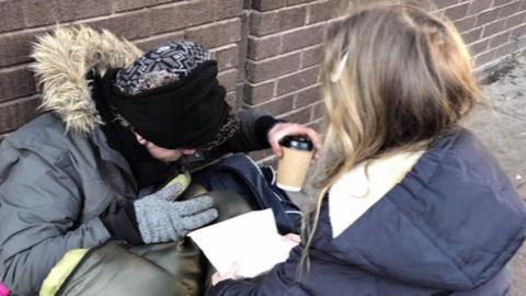 Helping a homeless person to have a hot drink