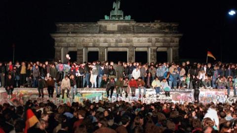 Archive image of Berlin Wall with people sitting on it