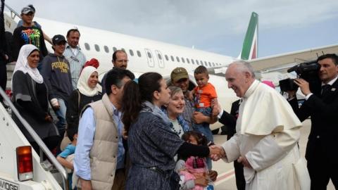 Pope Francis greets migrants stepping off a plane in Italy