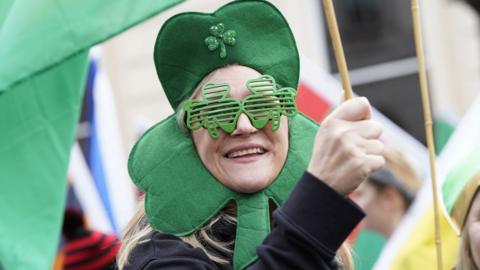 Woman wearing a clover head piece and glasses.
