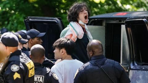 A protester at Emory University is led away by police