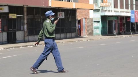 A woman walks on on an deserted street and closed shops, a day before anti government protests, in the central business district of Harare, Zimbabwe, 30 July 2020.