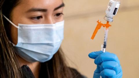 a nurse loads a syringe with vaccine