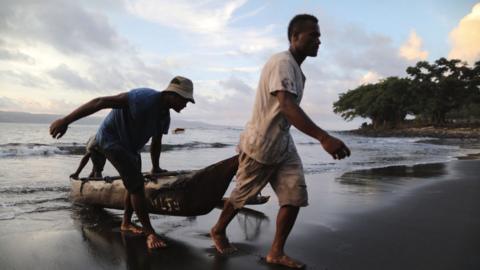 Villagers bring a boat ashore on the black sand beach in the village of Waisisi in Tanna, Vanuatu
