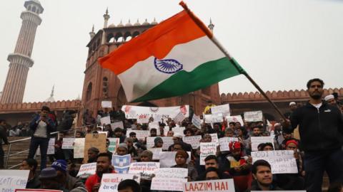 A student waves Indian flag during a sit in protest against the Citizenship Amendment Act (CAA) on the stairs of Jama Masjid in Old Delhi India on 19 December 2019