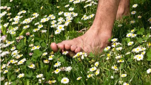 A man walking barefoot through a field