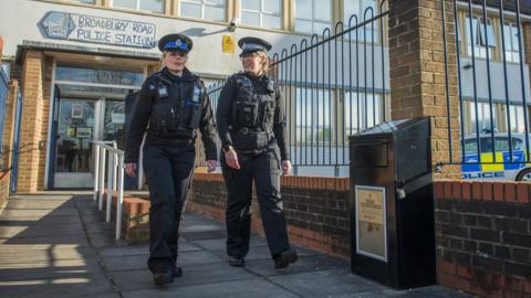 Knife bin and police officers walking past