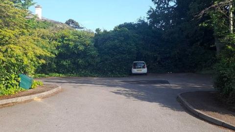 Idsall Drive car park surrounded by greenery with only one car parked on the site.