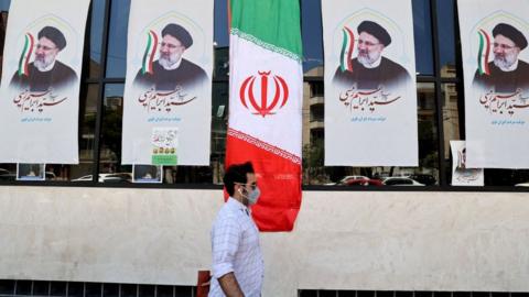 A man walks past an Iranian flag