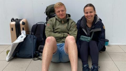Image of two travellers sat on the floor at Sheffield Station