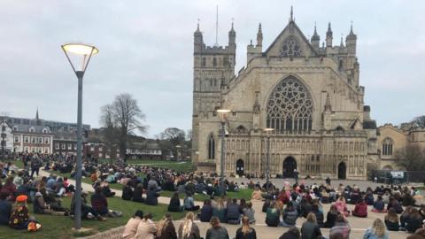People sitting down in a vigil outside Exeter Cathedral