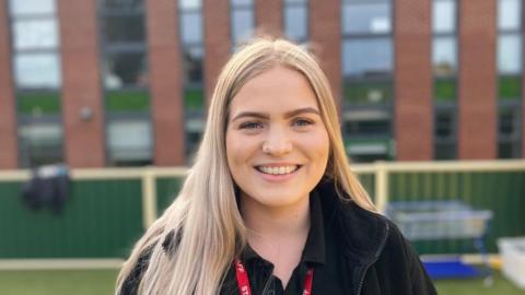 Young woman with long blond hair wearing a school lanyard