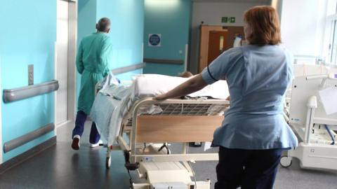 A bed-ridden patient being moved in a hospital corridor