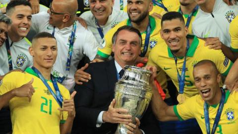 President of Brazil Jair Bolsonaro celebrates with the trophy and the players of Brazil after winning the Copa America Brazil 2019