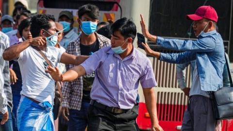 A military supporter points a sharp object as he confronts pro-democracy protesters during a military support rally in Yangon, Myanmar