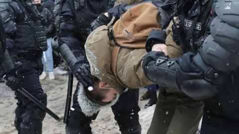 Protester held by police officers