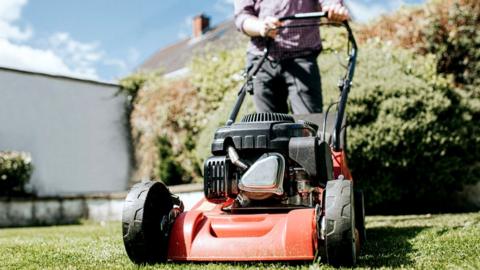 A man pushes a lawnmower