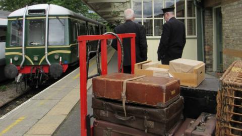 Historic selection of suitcases sits on platform next to train