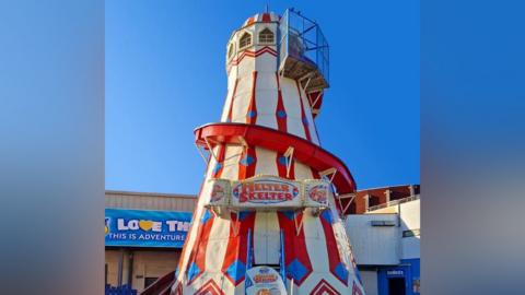 Helter Skelter ride. White and red tower with a red spiral slide going down.