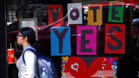 A pedestrian walks past a shop window with a display supporting a "Yes" vote in Sydney (04 October 2017)