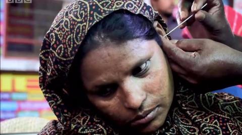 A Bangladeshi woman getting her ears cleaned.