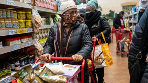 A woman wearing a mask moves her shopping cart December 3, 2020 in a Trader Joe's supermarket in New York City.