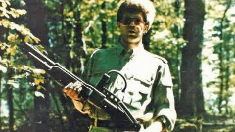 Handout picture shows a man holding a weapon in a forest