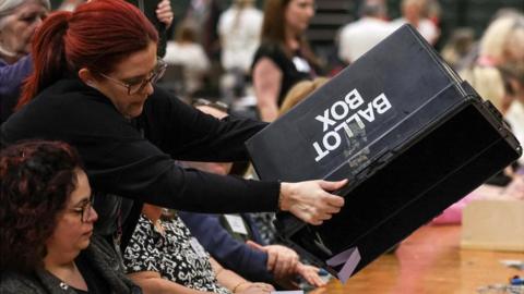An election official empties a ballot box to count the votes