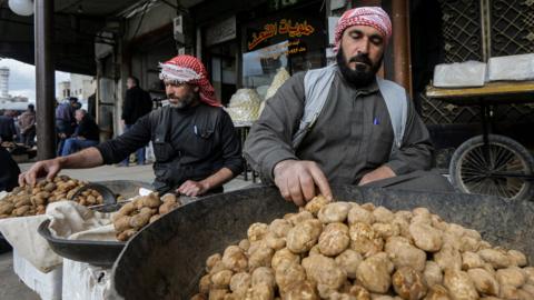 A merchant sorts through desert truffles at a stall in Hama, Syria (6 March 2023)