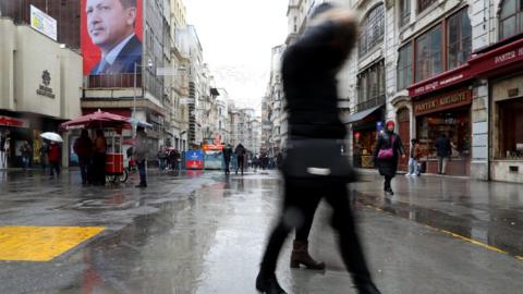 People walk in front of a giant poster of Turkish President Recep Tayyip Erdogan at Taksim Square in Istanbul, Turkey, 14 March