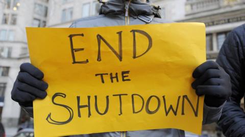 Protesters hold signs during a rally against the government shutdown in Boston on Friday, January 11, 2019