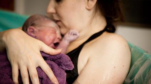 Woman in birthing pool with her newborn child