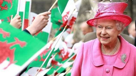 The Queen walks through a sea of Welsh flags
