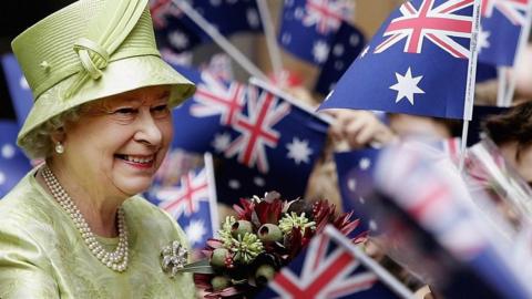 Queen Elizabeth II greeting people waving Australian flags.