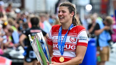 Ellie Rugman holds the Premiership trophy and walks around the pitch after winning the title