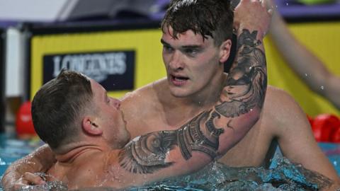 James Wilby is embraced by Adam Peaty after winning Commonwealth Games 100m breaststroke gold