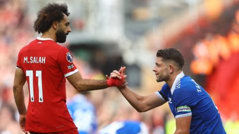 Liverpool's Mohamed Salah clasps hands with Everton's James Tarkowsk
