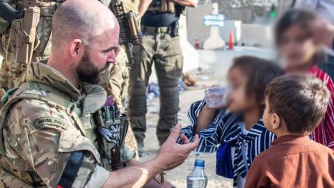 British solider offers water to child at Kabul airport on 23 August 2021