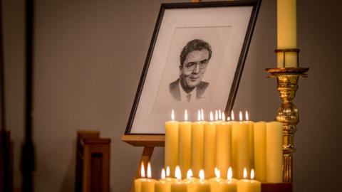 A portrait of John Hume surrounded by candles lit by members of his family and colleagues