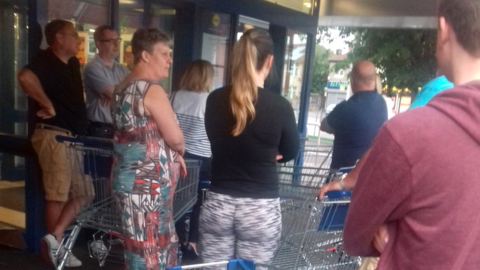 Shoppers queue outside supermarket Lidl for prosecco