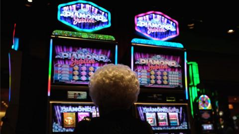 An older lady sits in front of neon-lit slot machines in Atlantic City, 2015