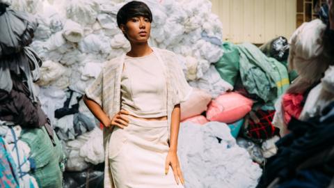 A fashion model poses in a room of textile offcuts in Cambodia