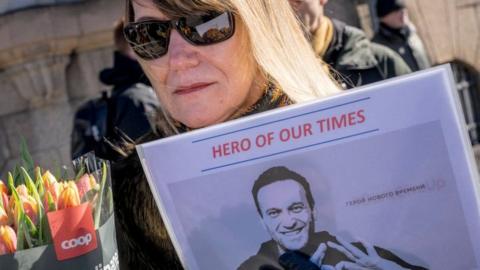 Protestors hold a picture of late Kremlin opposition leader Alexei Navalny reading 'hero of our times' in front of the Russian embassy in Copenhagen on March 17, 2024 during a presidential election in Russia