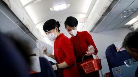 File photo: Flight attendants wearing face masks and gloves following the coronavirus disease (COVID-19) outbreak are seen inside a Sichuan Airlines aircraft before the flight takes off from Xichang Qingshan Airport in Xichang, Sichuan province, China June 16, 2020.