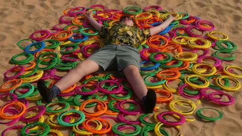Boy lying on plastic ring toys