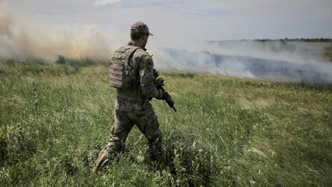 A Ukrainian serviceman walks through a field